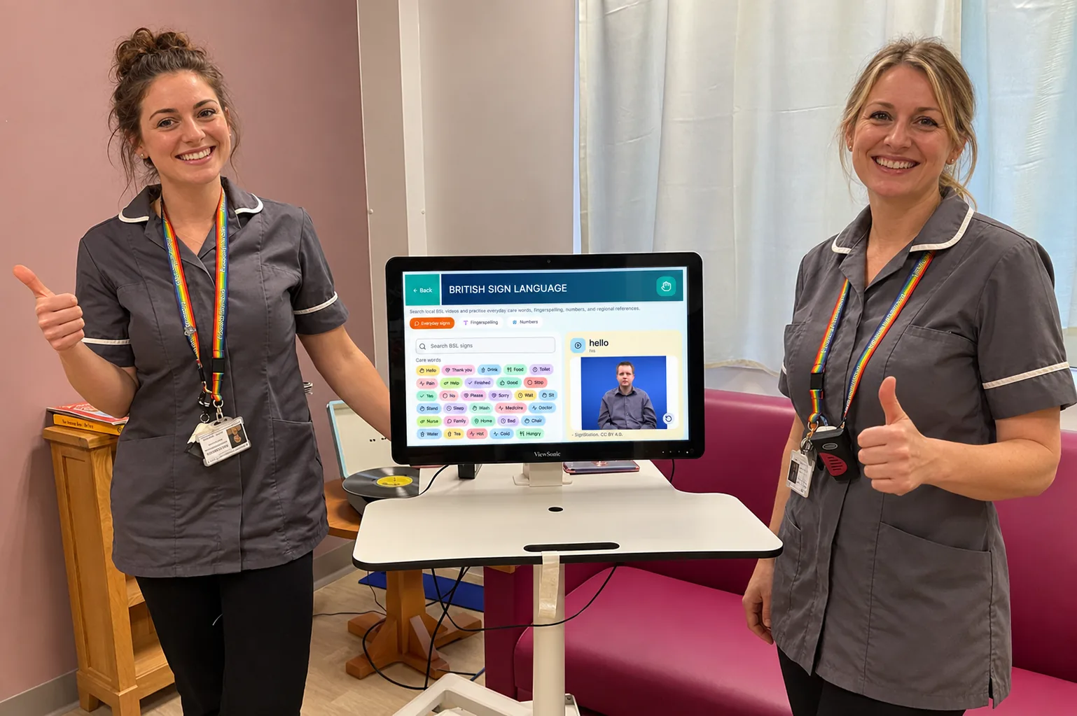 Two care team members with a TESS screen showing British Sign Language