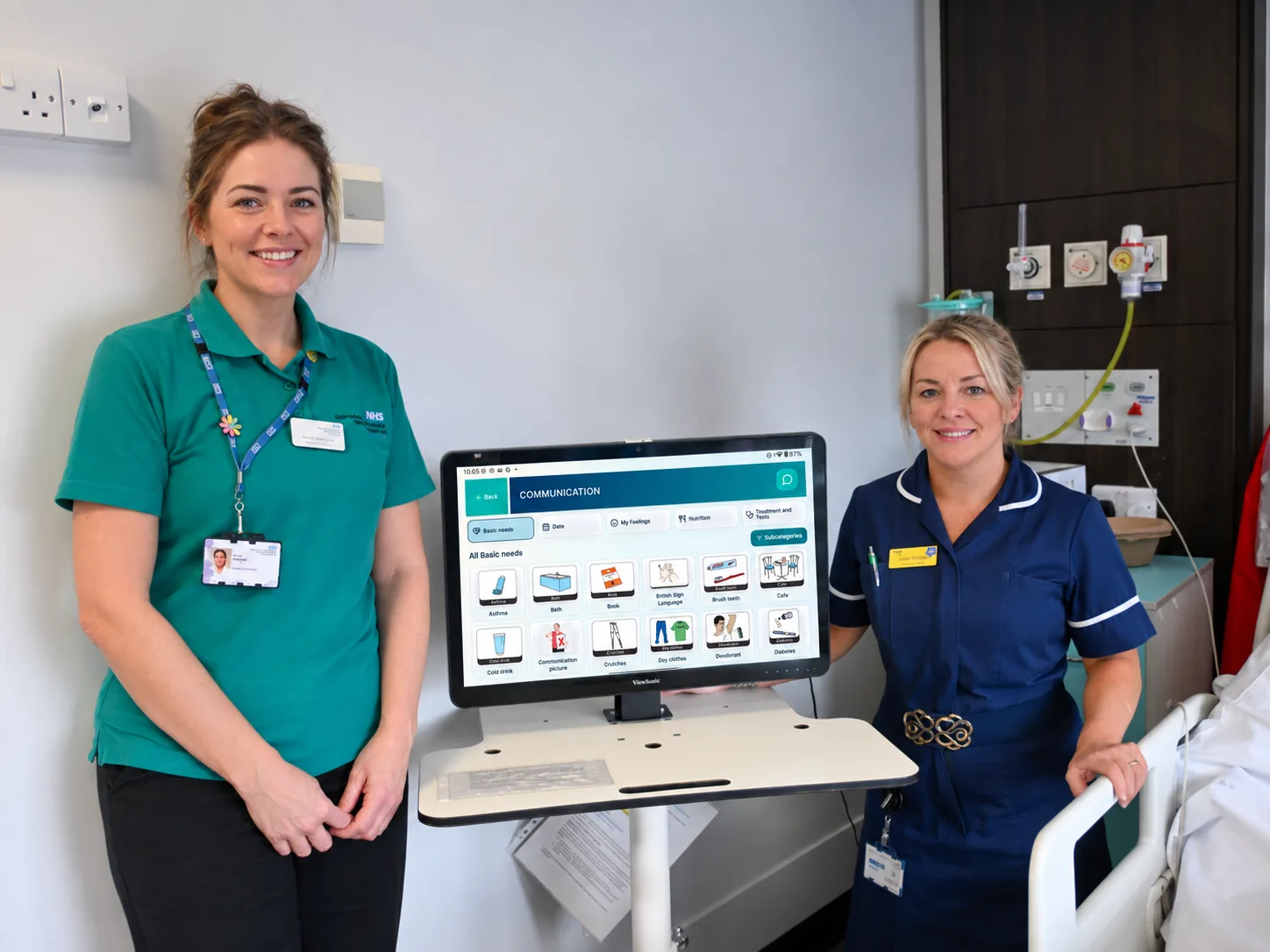 Care team members standing beside a TESS screen in a ward